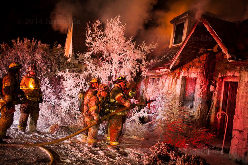 ACFR crews advance a hose line on a structure fire in winter conditions